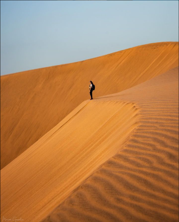 imagen tomada de una persona al borde de una de las dunas de maspalomas, en el sureste de la isla de gran canaria